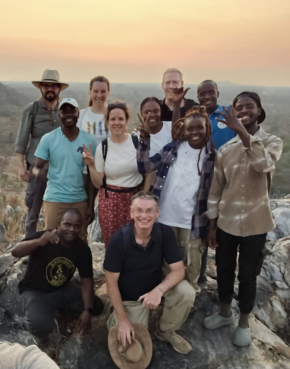 Visitors and community members together on Kashitu Hill at sunset